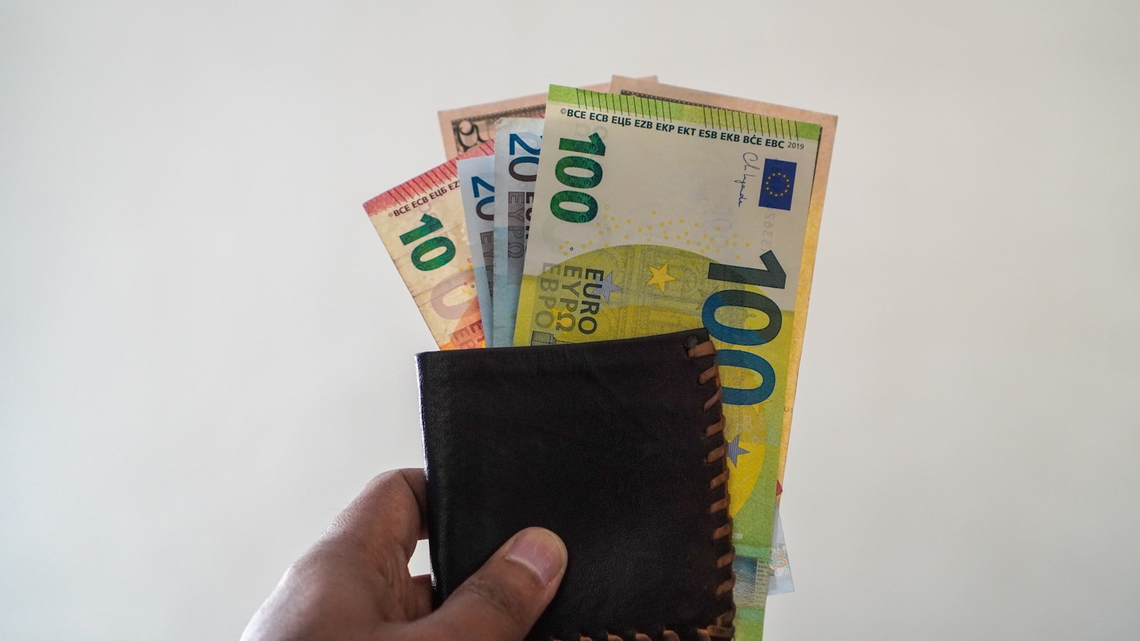 a hand holding a wallet full of money